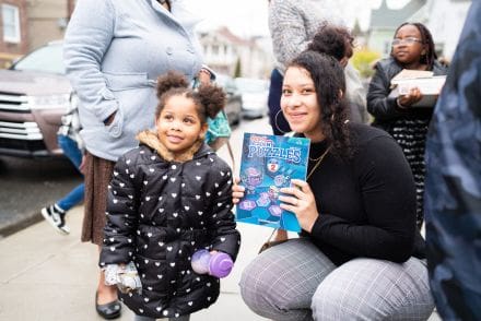 A woman and girl holding up a book.