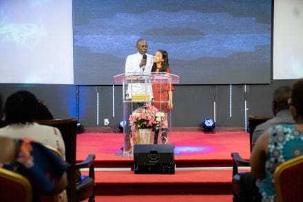 A man and woman standing at a podium in front of a crowd.