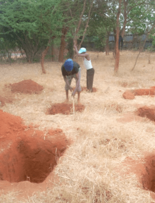 Two people in a field with dirt and trees