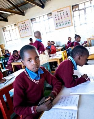 A group of children sitting at tables in a classroom.