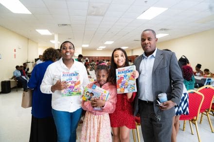 A group of people holding up books at an event.