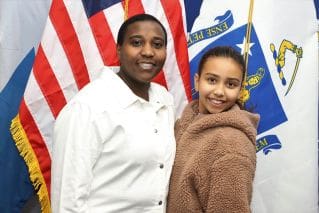 Two people standing next to each other in front of american flags.