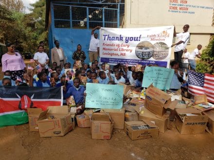 A group of people sitting around boxes in front of a building.