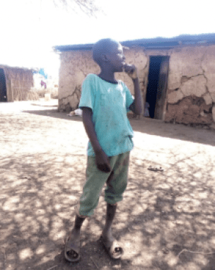 A young boy standing in front of a house.