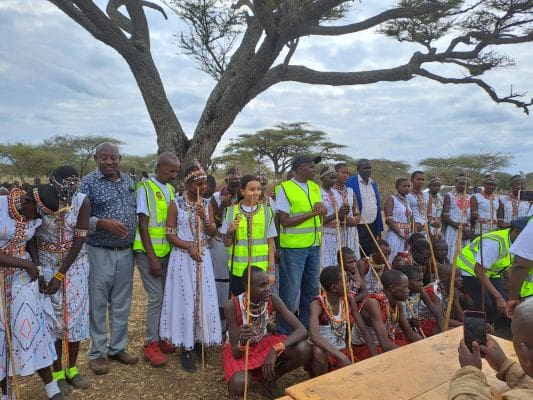 A group of people standing around under a tree.